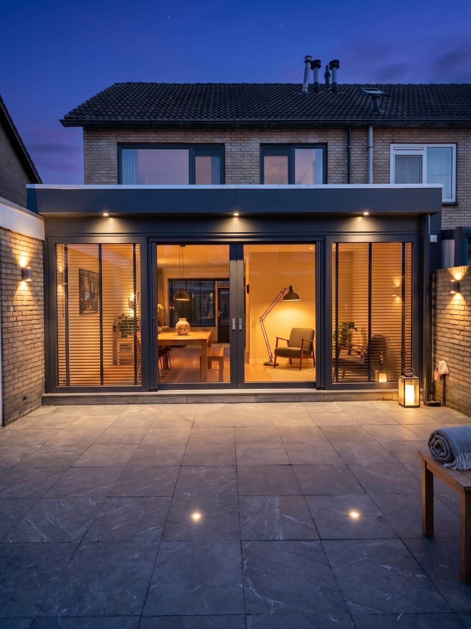 Interieur van een aanbouw met glazen daklicht en een schuifpui over de volle breedte naar de tuin